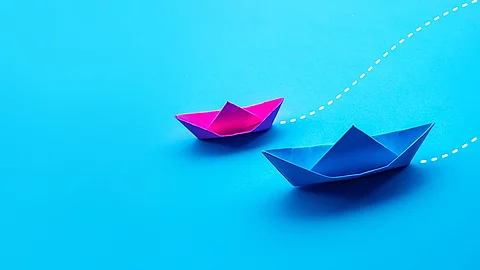 Partner Zwei Papierboote in pink und blau fahren gemeinsam in eine Richtung.